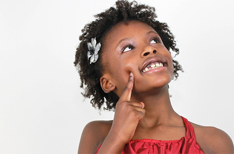 Little girl with flower in her hair looking up and thinking